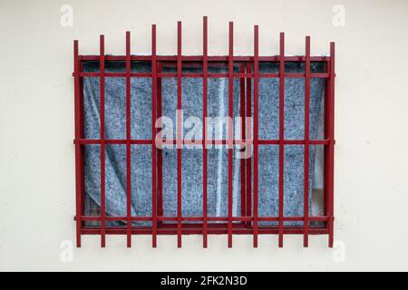 Window with Red Bars and a Blanket as a Curtain Stock Photo