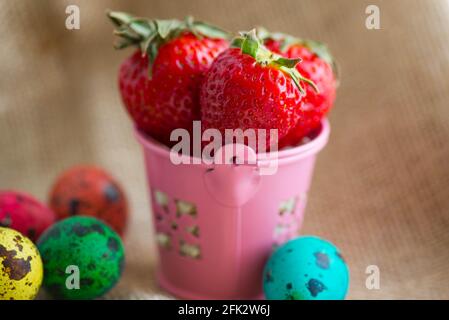 red strawberries in a pink bucket and Easter eggs Stock Photo