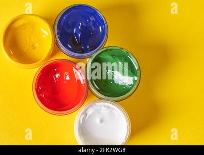 five colors of gouache stands on a yellow background Stock Photo