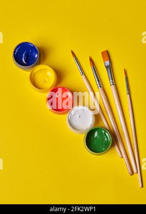 four tassels and colored gouache stands on a yellow background Stock Photo