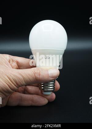 Man's hand holding LED light bulb. Close-up. Isolated on black. Stock Photo