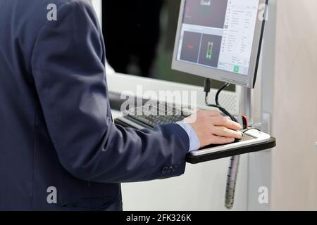 Engineer controls modern manufacturing equipment using a computer. Selective focus. Stock Photo
