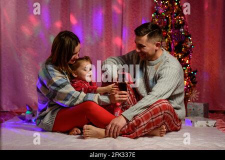 Portrait Of Excited Family Wearing Pajamas Sitting On Stairs On 