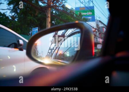 A car wing mirror with the glow of headlights and reflections of buildings. Stock Photo