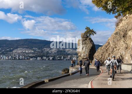 People cycling in Stanley Park Seawall Siwash Rock in sunny day. Vancouver, BC, Canada. Stock Photo