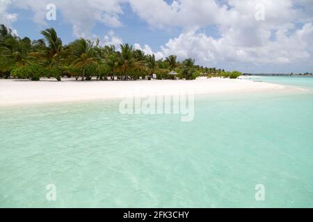 Palm trees by the white sand beach on Paradise Island in the Maldives. Monsoon clouds gather over the tropical island. Stock Photo