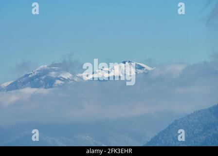 Panoramic view of the mountains. In the foreground clouds, in the middle snow-covered winter forest. Lago-Naki, The Main Caucasian Ridge, Russia Stock Photo