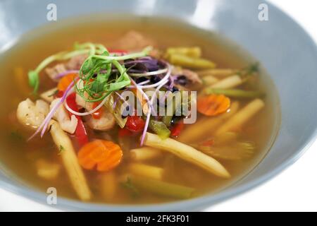Close up of hot delicious healthy vegetables soup with different fresh greens. Concept of eating appetizing soup with carrots, potatoes, beans,cauliflower and natural seasoning.  Stock Photo