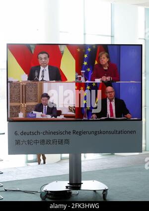 Berlin, Germany. 28th Apr, 2021. German Chancellor Angela Merkel and German Economics Minister Peter Altmaier (both CDU - bottom right) are seen on a television screen in the Chancellery. They are taking part in talks with Chinese Premier Li Keqiang (top left) and the Chairman of China's National Development and Reform Commission (NDRC), He Lifeng, as part of the sixth Sino-German intergovernmental consultations. This time, for the first time, there was only one video conference due to the Corona pandemic. Credit: Michele Tantussi/Reuters/Pool/dpa/Alamy Live News Stock Photo