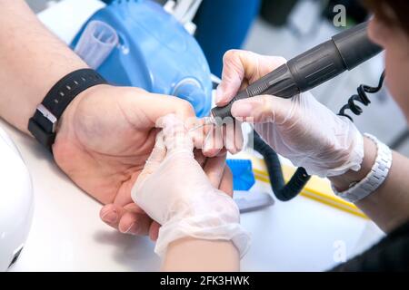 Mens manicure. A manicure master makes a hardware manicure for a man in the salon. Beauty industry. Stock Photo