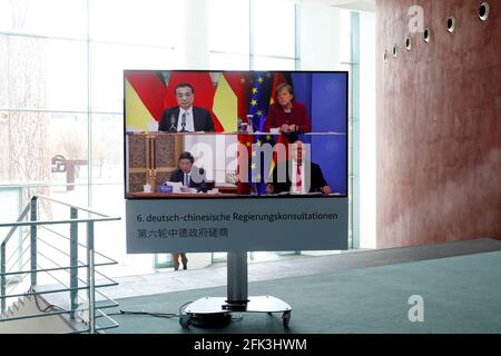 Berlin, Germany. 28th Apr, 2021. German Chancellor Angela Merkel and German Economics Minister Peter Altmaier (both CDU - bottom right) are seen on a television screen in the Chancellery. They are taking part in talks with Chinese Premier Li Keqiang (top left) and the Chairman of China's National Development and Reform Commission (NDRC), He Lifeng, as part of the sixth Sino-German intergovernmental consultations. This time, for the first time, there was only one video conference due to the Corona pandemic. Credit: Michele Tantussi/Reuters/Pool/dpa/Alamy Live News Stock Photo