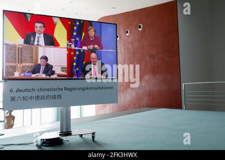 Berlin, Germany. 28th Apr, 2021. German Chancellor Angela Merkel and German Economics Minister Peter Altmaier (both CDU - bottom right) are seen on a television screen in the Chancellery. They are taking part in talks with Chinese Premier Li Keqiang (top left) and the Chairman of China's National Development and Reform Commission (NDRC), He Lifeng, as part of the sixth Sino-German intergovernmental consultations. This time, for the first time, there was only one video conference due to the Corona pandemic. Credit: Michele Tantussi/Reuters/Pool/dpa/Alamy Live News Stock Photo
