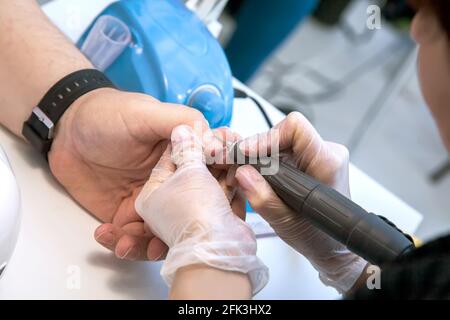 Mens manicure. A manicure master makes a hardware manicure for a man in the salon. Beauty industry. Stock Photo