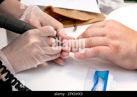 Mens manicure. A manicure master makes a hardware manicure for a man in the salon. Beauty industry. Stock Photo