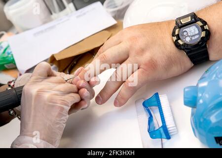 Mens manicure. A manicure master makes a hardware manicure for a man in the salon. Beauty industry. Stock Photo