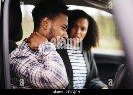 Couple inside car after road traffic accident with male driver suffering whiplash injury Stock Photo
