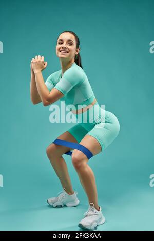 Joyful young woman doing exercise with resistance band Stock Photo