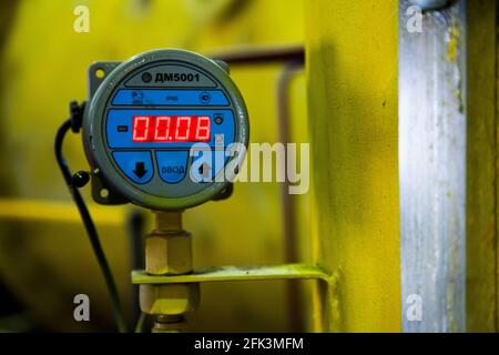 Close up photo of electronic flow meter with digital display. Blurred yellow background, low depth of field. Stock Photo