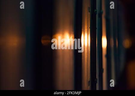 Abstract blurred view of shiny metal pipes in back light. Warm-color stripes background. Industrial photo. Stock Photo