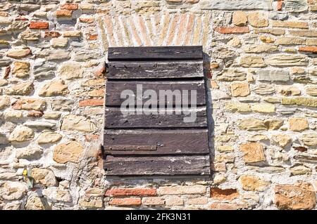 An old wooden shutter that closes a window of a stone house in a medieval Italian village (Pesaro, Italy, Europe) Stock Photo