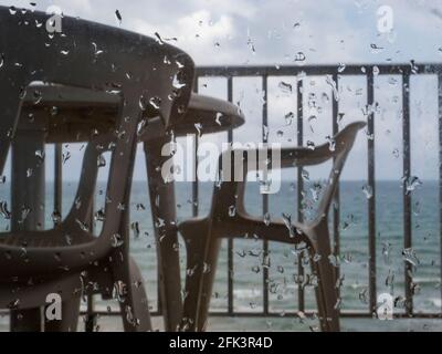 Empty terrace in a beachside apartment, seen from behind rain-splashed glass Stock Photo