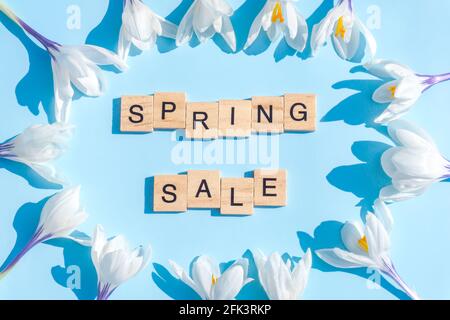 Spring Sale wooden letters sign surrounded by white crocus flowers on gentle blue background. Flat lay, soft floral early Spring composition banner Stock Photo