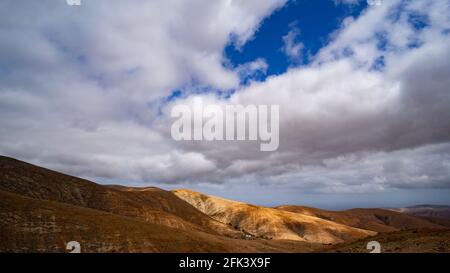 Sunlight falling through a gap in the clouds on a mountain range shot with a very low horizon Stock Photo