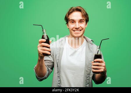 Man holds glass bottles with straws, isolated on green background Stock Photo