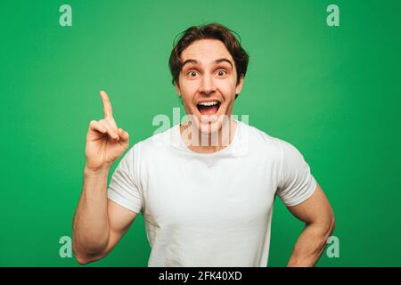 Young man looks he came up with an idea, isolated on green background Stock Photo