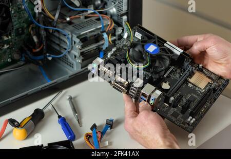 A technician is holding the motherboard in a desktop case. Stock Photo