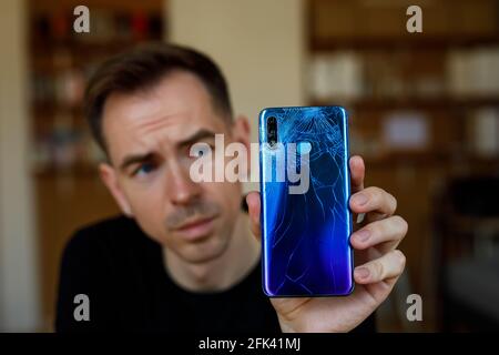 The sad man holds a broken smartphone with cracks Stock Photo