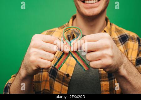 Young man holds jelly candy like Red ribbon, isolated on green background Stock Photo