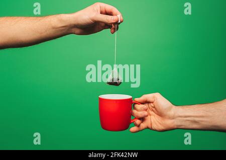 Close up man is preparing tea, isolated on green background Stock Photo