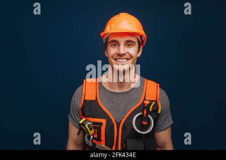 Cute builder in a helmet is smiling, isolated over blue background Stock Photo