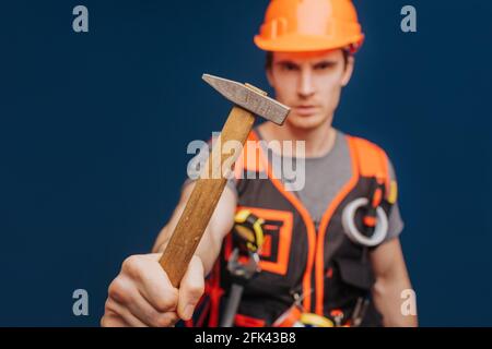 Close up builder in a helmet with a hammer, isolated over blue background Stock Photo