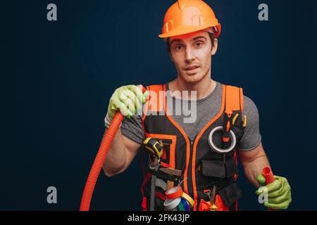 Curious builder is holding the trumpet, isolated over blue background Stock Photo