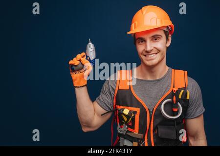 Attractive builder is having equipment in arm, isolated over blue background Stock Photo