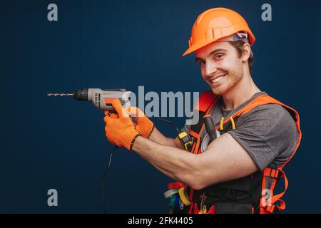 Builder is having equipment in arm and smiling, isolated over blue background Stock Photo