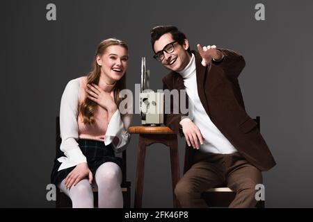 laughing man pointing with finger while watching comedy near woman isolated on black Stock Photo