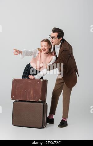 amazed couple looking away near vintage suitcases on grey background Stock Photo