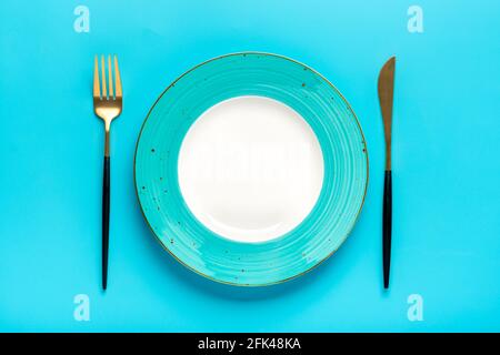 empty round blue plate, fork, knife on blue table Top view Flat lay Dishes for breakfast, lunch or dinner Mock up Stock Photo