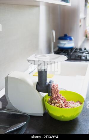 a meat grinder grinds meat into minced meat, in a home kitchen. copyspace Stock Photo
