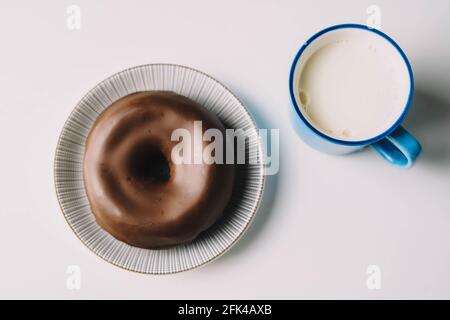Delicious fresh chocolate donut on white background. Appetizing tasty glazed donut ready to eat with a cup of fresh milk Stock Photo