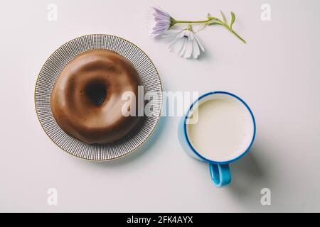 Delicious fresh chocolate donut on white background. Appetizing tasty glazed donut ready to eat with a cup of fresh milk Stock Photo