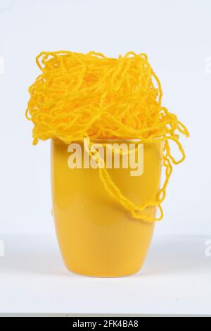 A large yellow mug with knitted threads. Stock Photo