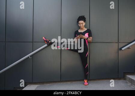 Young fitness woman runner stretching legs before city jog Stock Photo