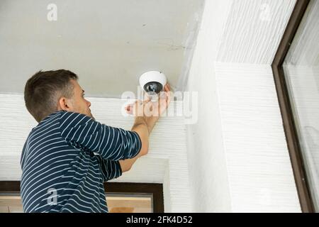Man installs security camera in private house under construction. Stock Photo