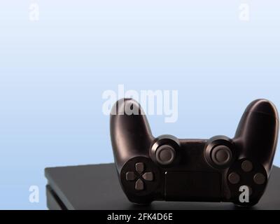 Control of new generation electronic games. Black game controller isolated on blue background. Gamepad. Wireless joytsick for PC games. Stock Photo
