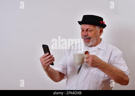 Smiling senior man talking on the phone and having a cup of coffee Stock Photo