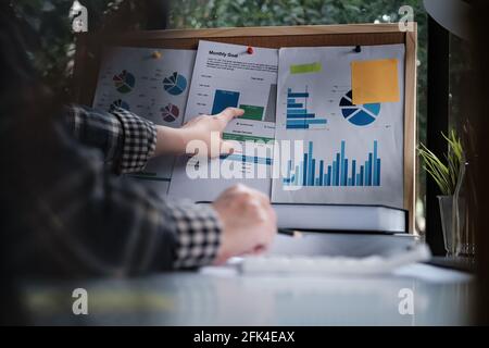 Rear view of female employee meeting via video call with employee brief the stock market chart. Stock Photo